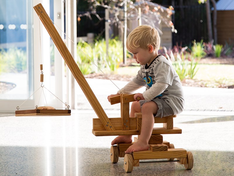 Young child playing with a wooden toy crane